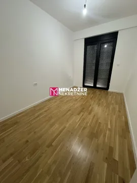 Prazna soba sa parketom i tamnim roletnama na balkonskim vratima. - image 6