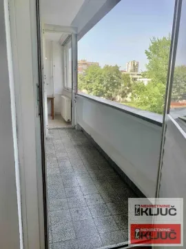 Dugačka popločana terasa sa pogledom na gradsko zelenilo i okolne zgrade. - image 6