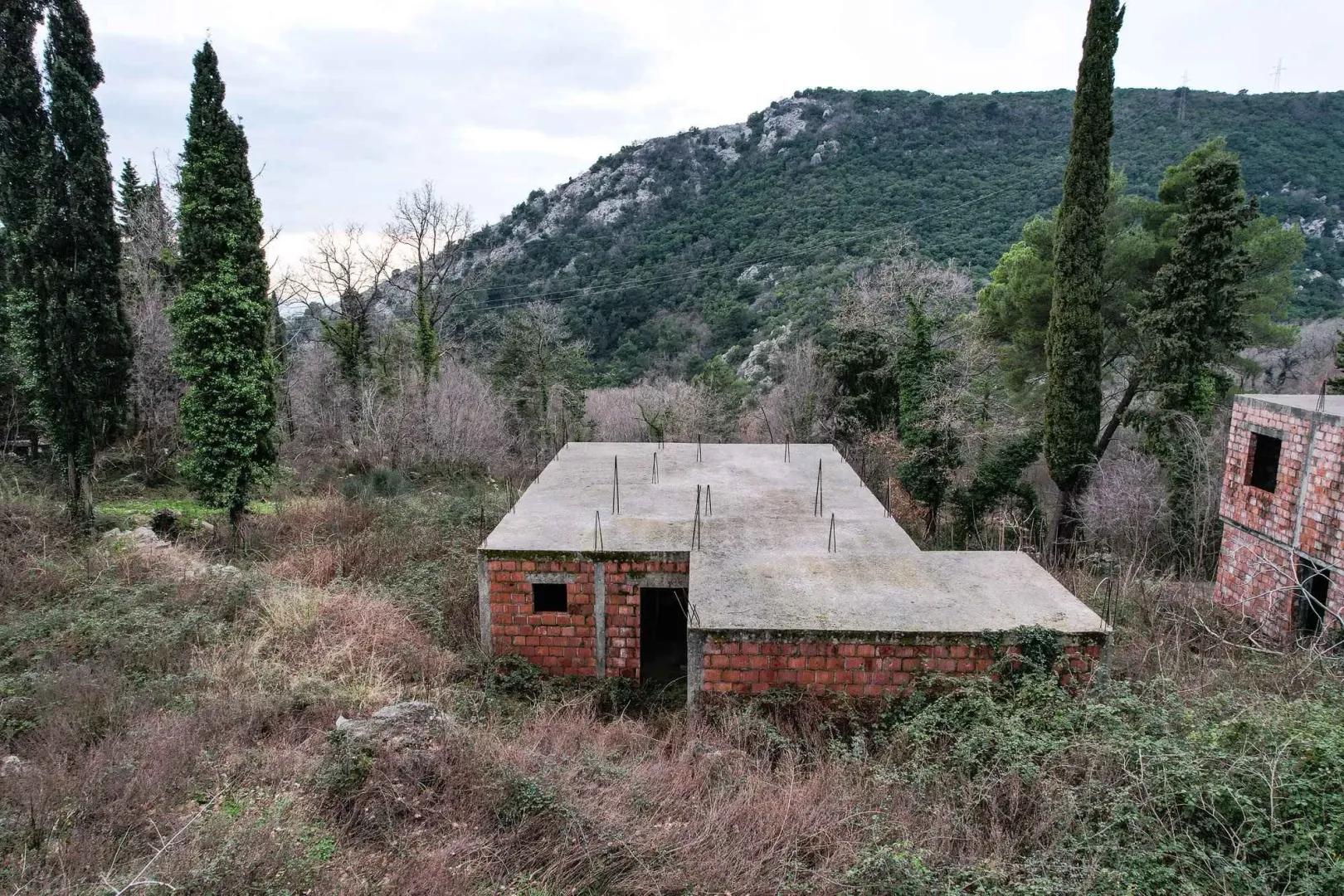 Nedovršena kuća okružena prirodom i brdima.