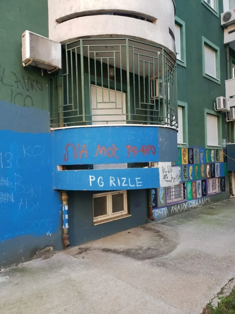 Exterior of a residential building with a terrace and graffiti on the facade.