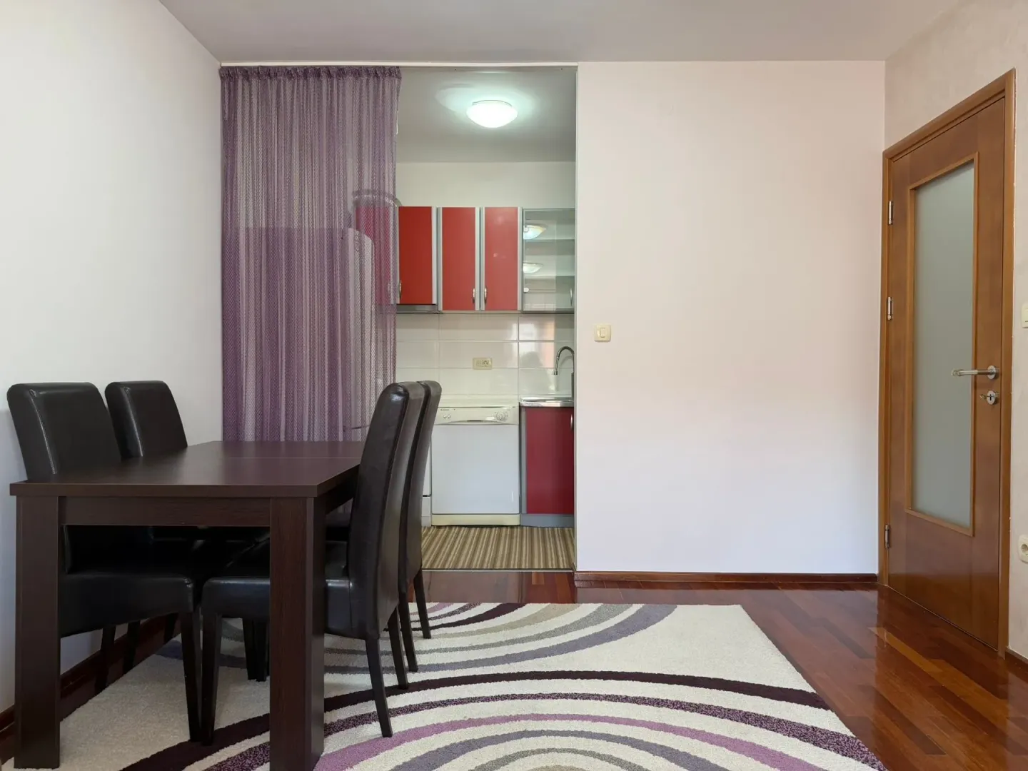 Dining area with seating set and a view of the kitchen in the background.