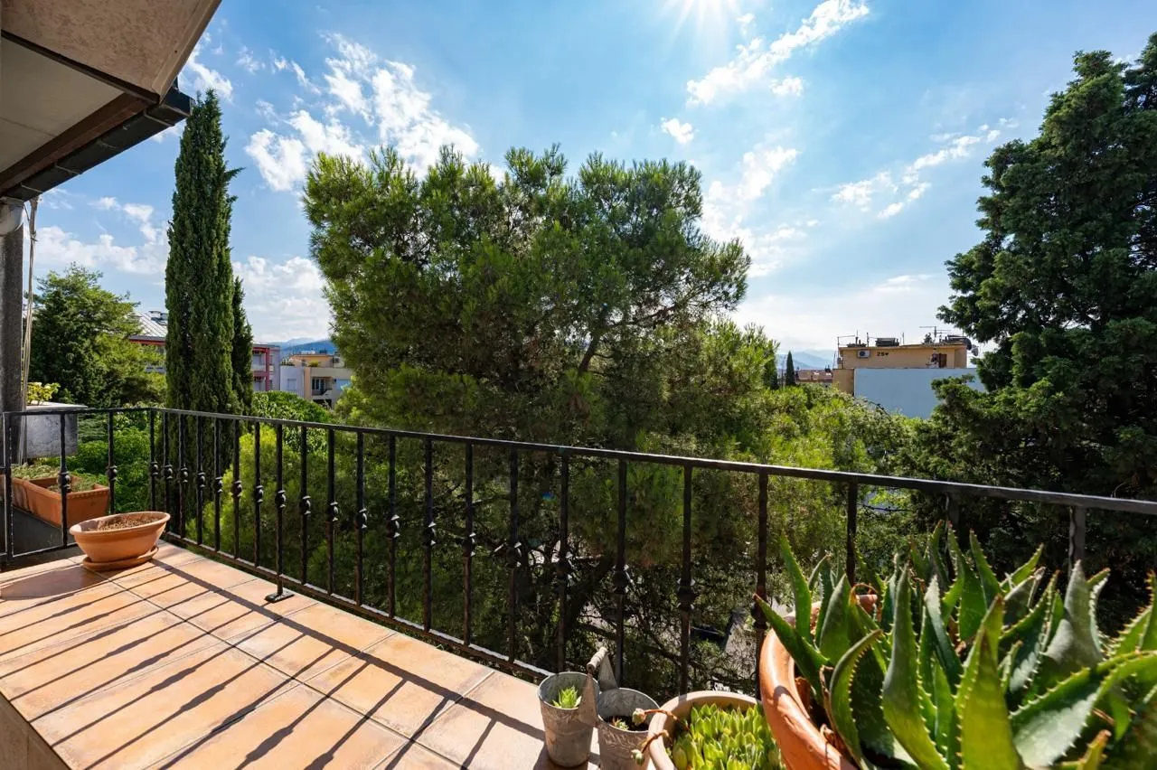 Furnished balcony with potted plants and views of greenery and surroundings.