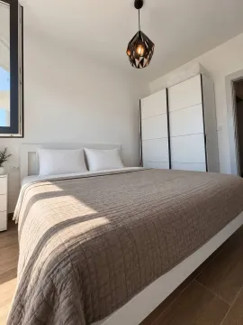 Svjetla i uredna spavaća soba sa bračnim krevetom, bijelim garderoberom i modernim lusterom. - image 4