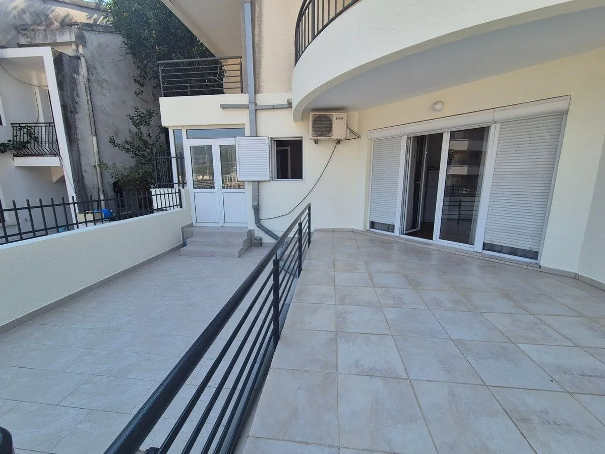 Large tiled terrace in front of the apartment entrance.