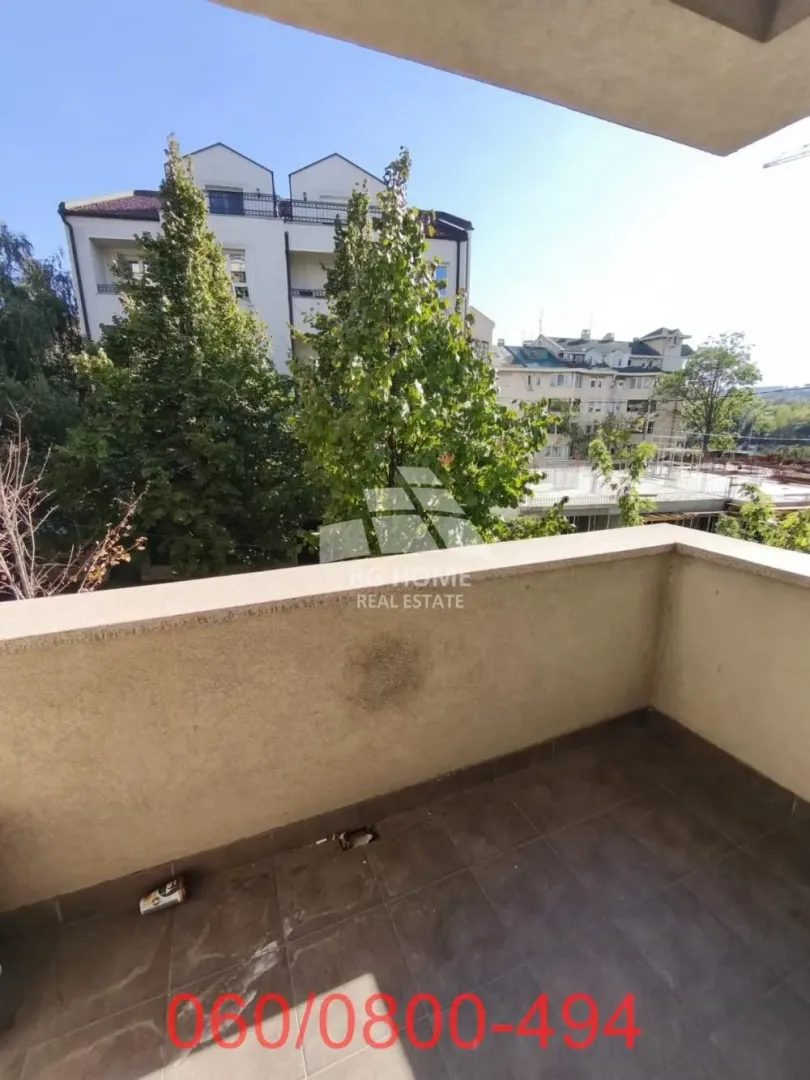 View from the tiled balcony overlooking surrounding buildings and greenery.