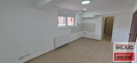 Prazna soba sa svetlim zidovima, prozorom i vratima koja vode u kupatilo. - image 5