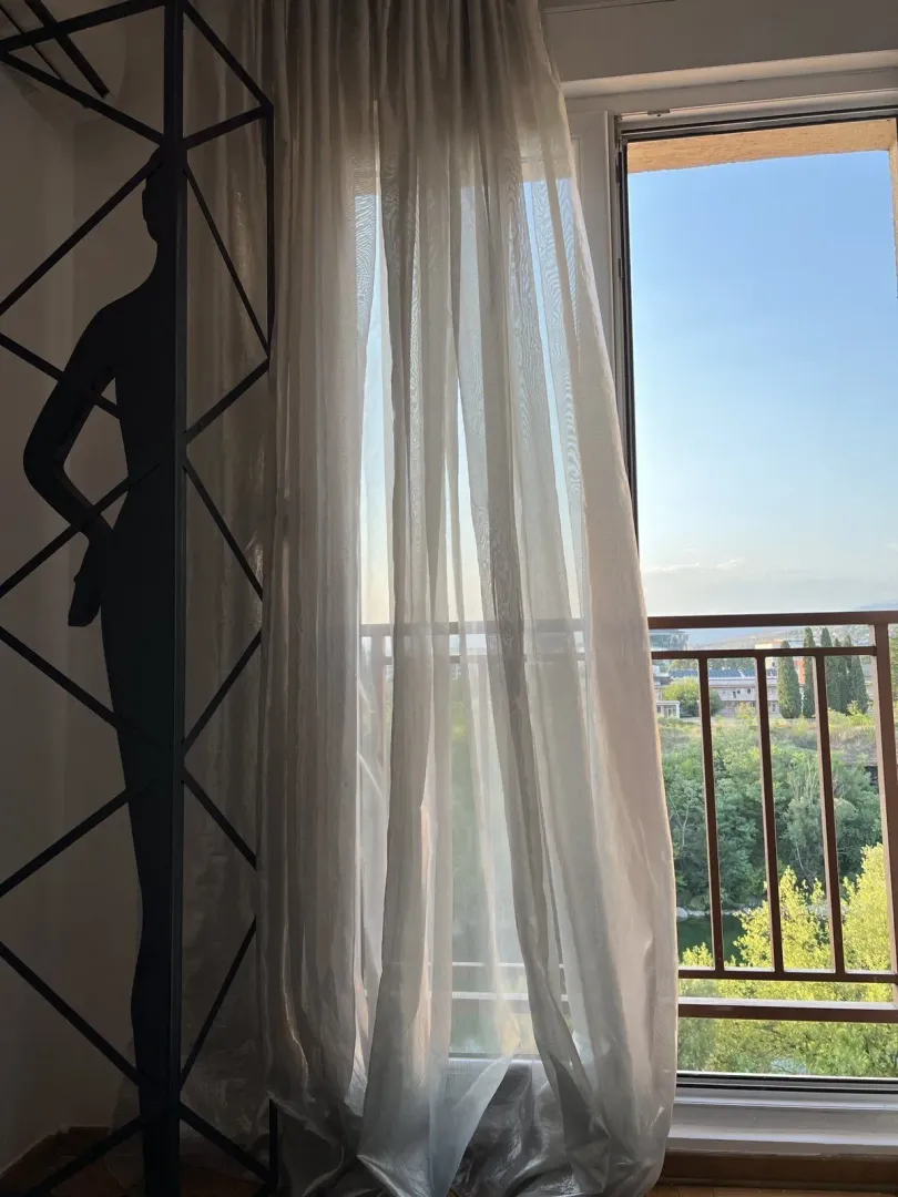 Pogled na balkonska vrata sa laganim bijelim zavjesama.