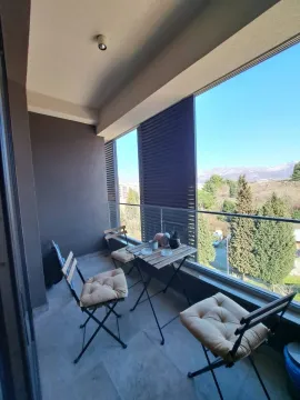 Namješten balkon sa stolom i stolicama i pogledom na prirodu. - image 10