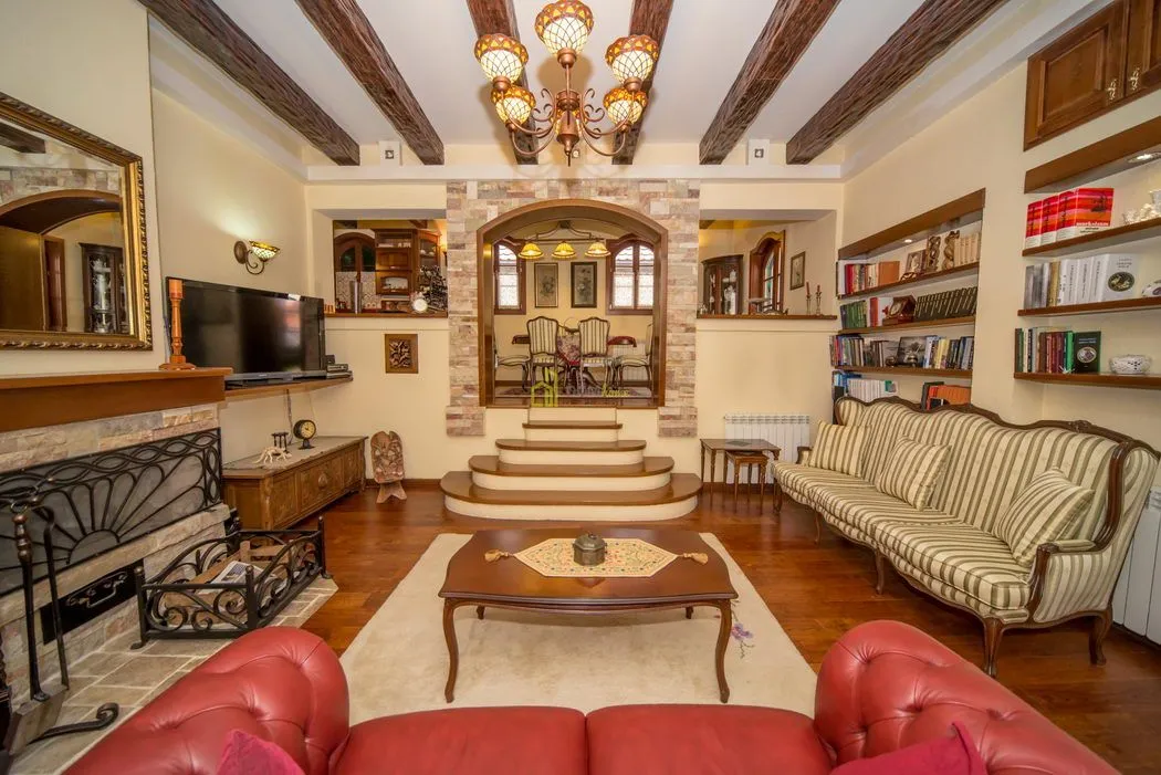 Traditionally furnished living room with a fireplace and wooden ceiling beams.
