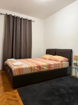 Furnished bedroom with a double bed, dark curtains, and parquet flooring. - image 7