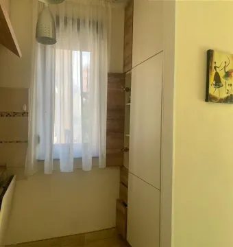 Part of the kitchen with white cabinets, a window with a curtain, and a pendant lamp. - image 5