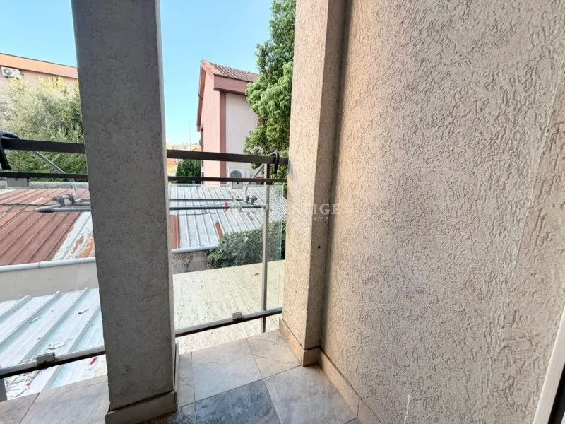 Pogled sa popločane terase na okolne zgrade i krovove.