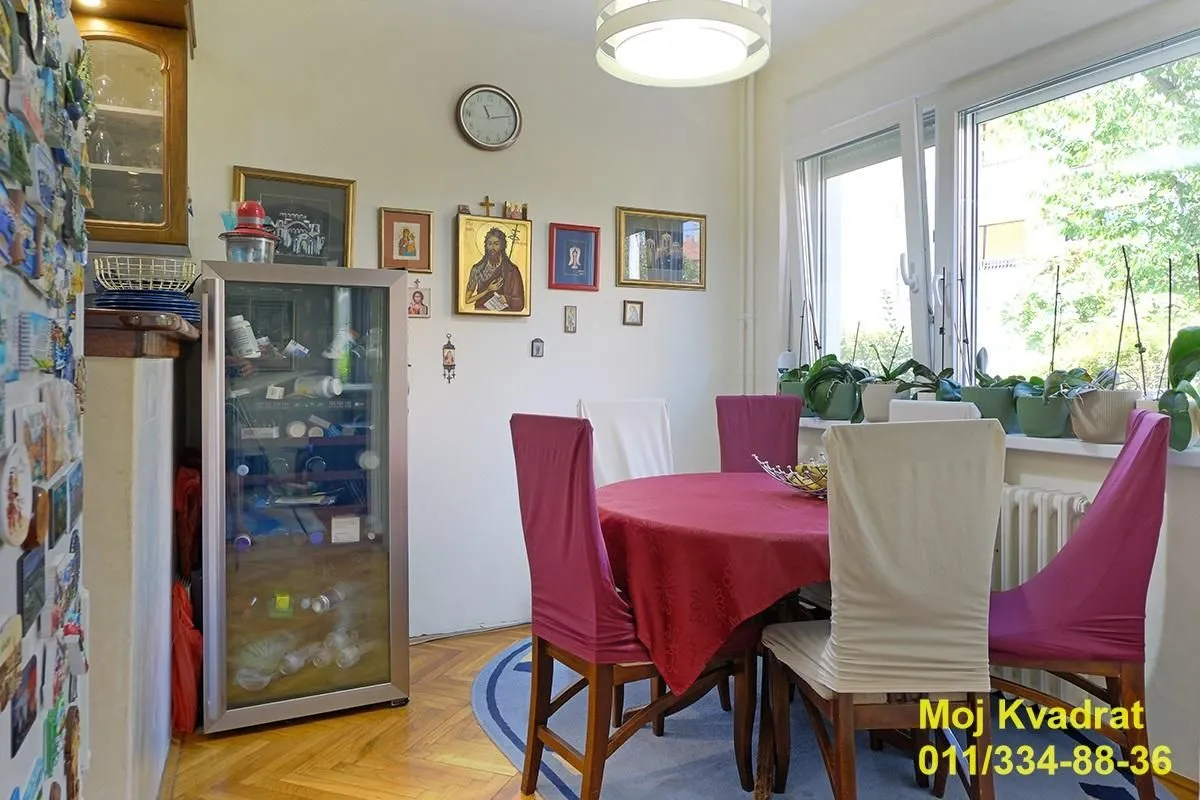 Trpezarija sa stolom, stolicama i vitrinom u stanu.