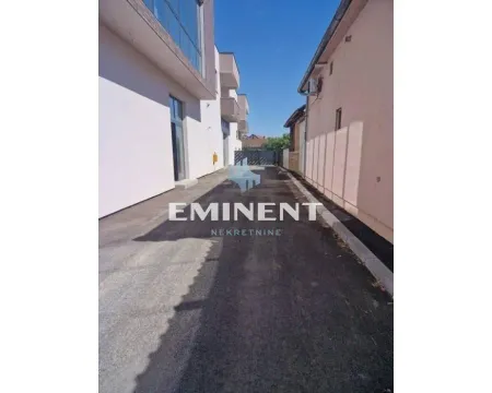 Paved driveway and yard alongside the building exterior. - image 12