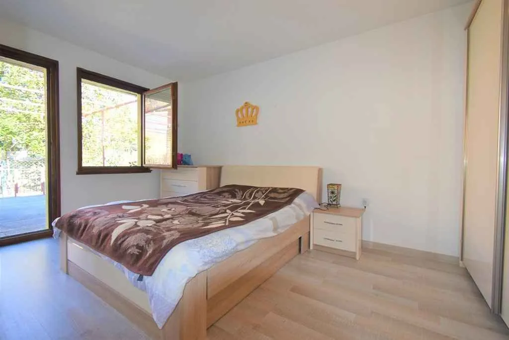 Bright bedroom with a double bed, nightstand, and wardrobe.