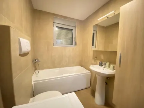 Compact bathroom with a bathtub, washbasin, and built-in cabinet in beige tones. - image 13
