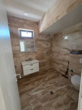 Kupatilo obloženo keramičkim pločicama sa tuš kabinom i umivaonikom. - image 6