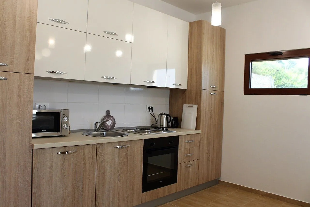 Modern kitchen with light wooden elements and white upper cabinets.
