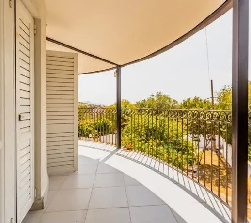 Spacious semicircular balcony with a view of the courtyard and greenery.