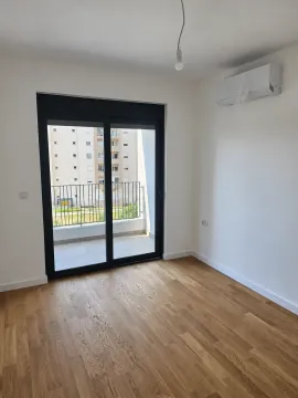 Prazna soba sa drvenim podom, klima uređajem i balkonskim vratima. - image 8
