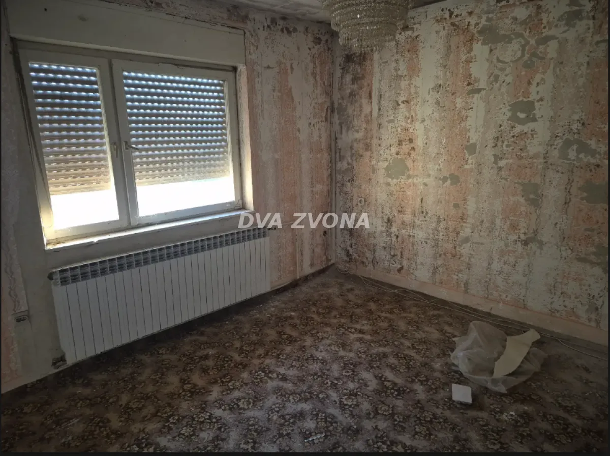 Prazna prostorija sa prozorom i radijatorom kojoj je potrebna adaptacija.