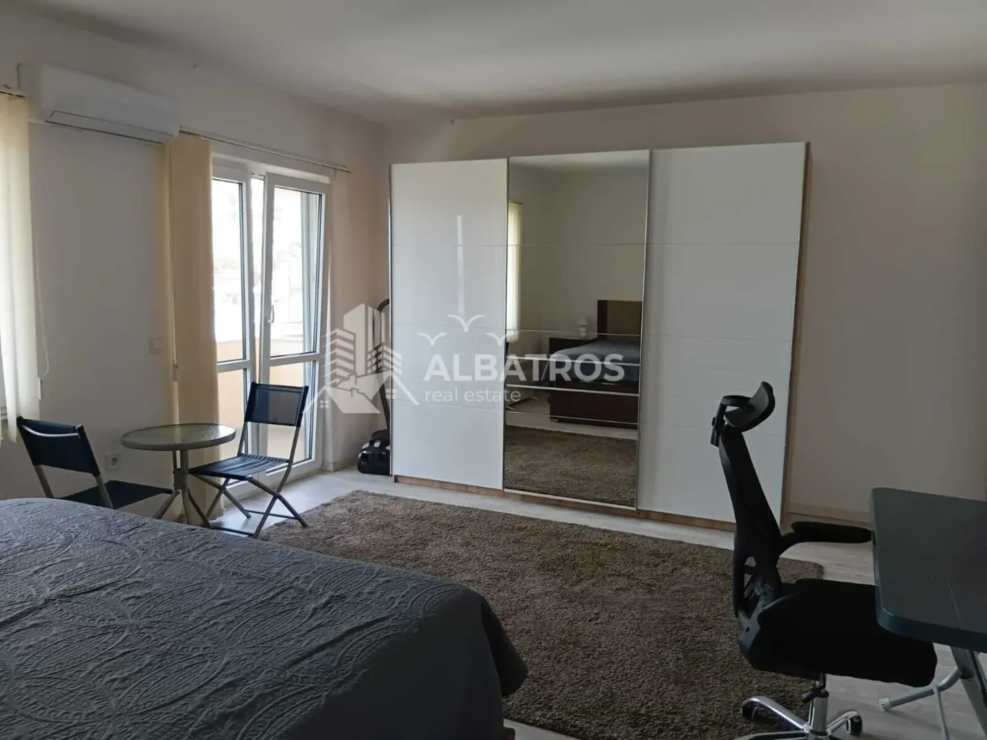 Furnished bedroom with a large wardrobe, bed, and desk.