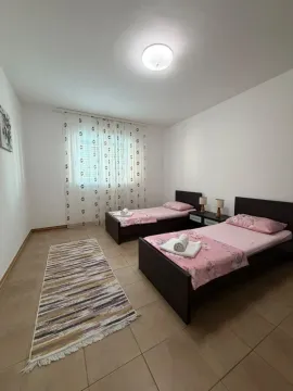 Spavaća soba sa dva singl kreveta i prozorom sa bijelim zavjesama. - image 7