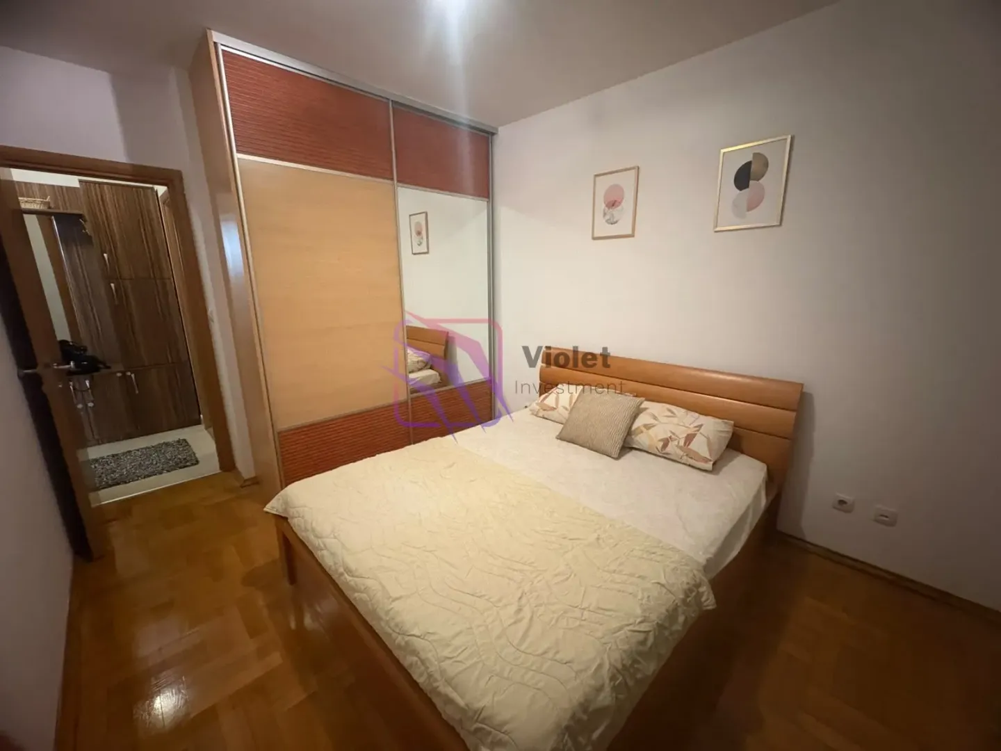 Namještena spavaća soba sa bračnim krevetom i velikim ormarom.