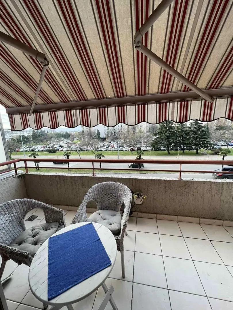 Balkon sa garniturom za sjedenje i prugastom tendom.