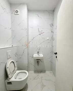 Small bathroom lined with marble tiles featuring a toilet and a sink. - image 9