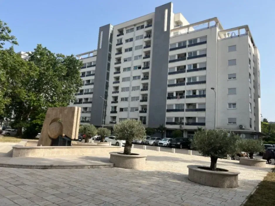 Exterior view of the residential building with a landscaped square and greenery.