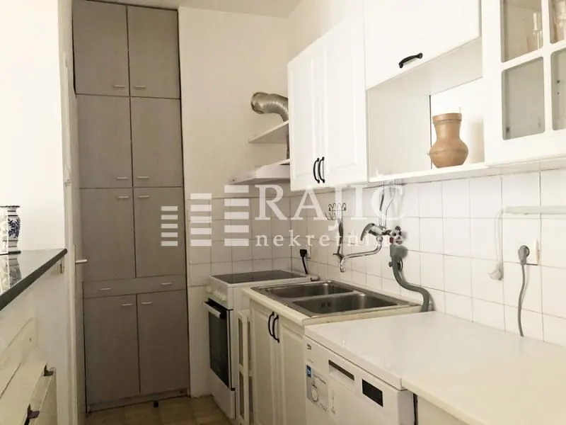 Small equipped kitchen with white cabinets and a tall storage unit.