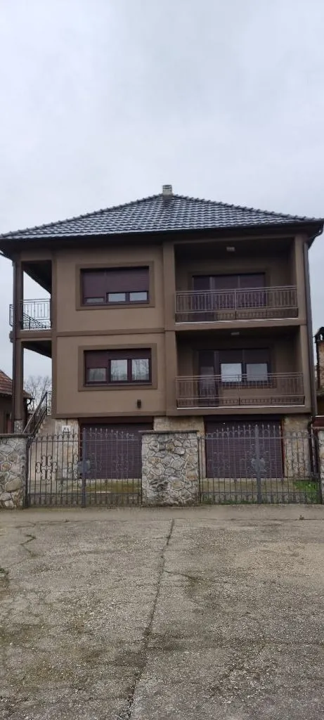 Spoljašnji izgled dvospratne kuće sa garažama i ogradom.