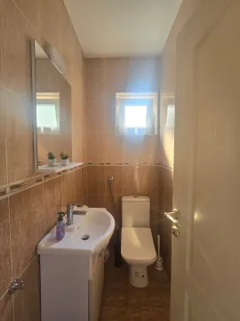 Manje kupatilo sa umivaonikom, wc šoljom i ogledalom obloženo keramičkim pločicama u bež tonovima. - image 14