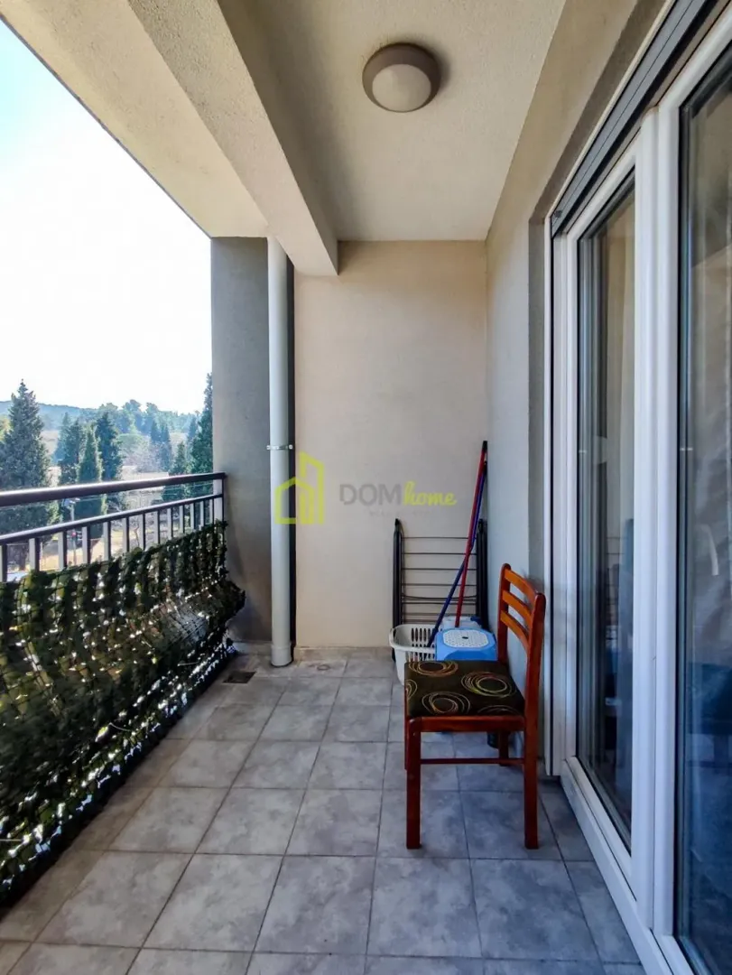 Covered balcony space with glass doors and a view of greenery.
