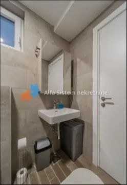 Compact bathroom with a sink, mirror, and neutral-toned tiles. - image 11