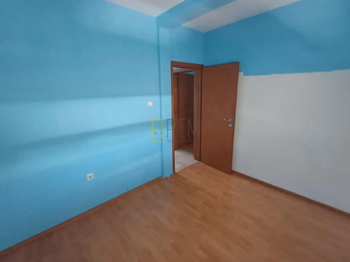 Prazna soba sa laminatom i plavim i bijelim zidovima.