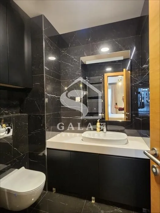 Modern bathroom with black marble tiles and a built-in vanity cabinet.