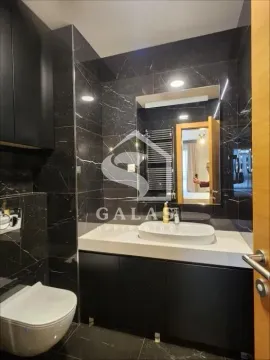 Modern bathroom with black marble tiles and a built-in vanity cabinet. - image 6