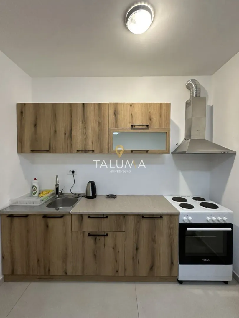 Small kitchen with wooden cabinets, sink, and stove.