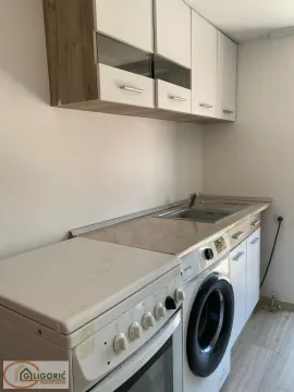 Small kitchen with a sink, stove, washing machine, and upper cabinets. - image 12