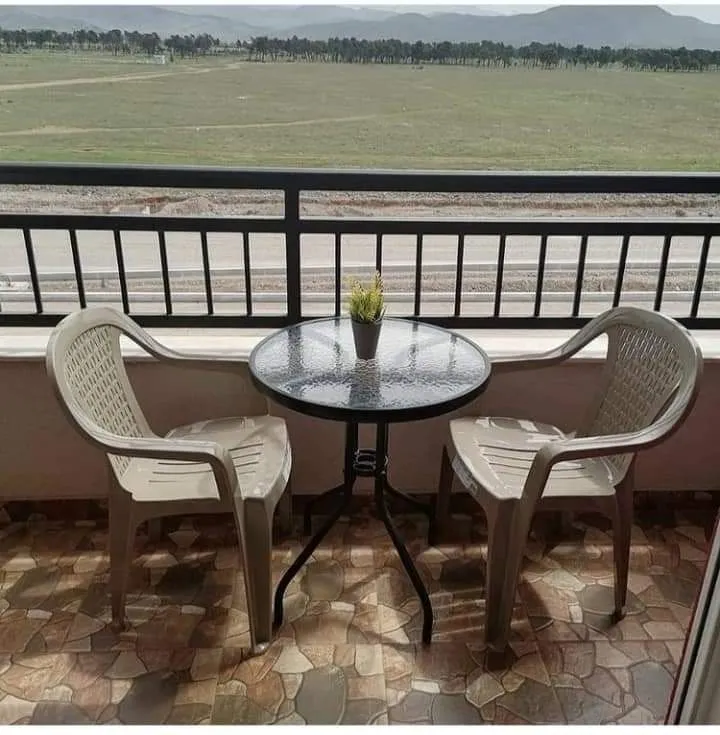 Balcony with a table and two chairs overlooking nature.