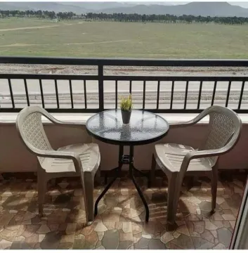 Balcony with a table and two chairs overlooking nature. - image 21