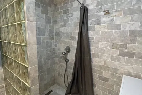 Prikaz tuš kabine sa sivim pločicama i staklenim blokovima. - image 10