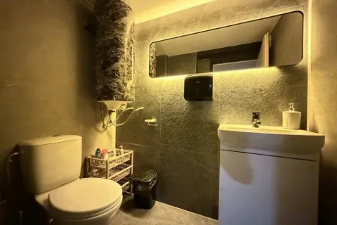 Modern bathroom equipped with a toilet, washbasin, and backlit mirror. - image 10