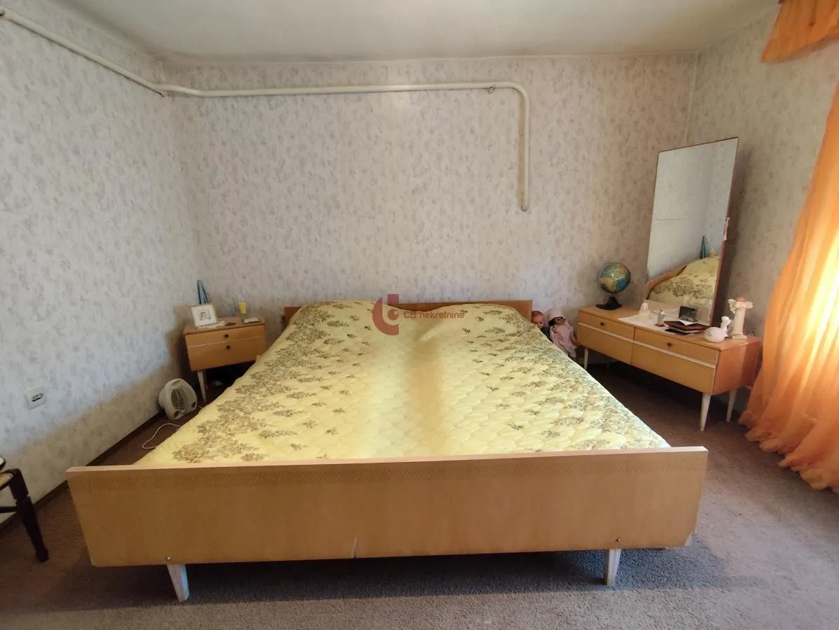 Furnished bedroom with a double bed, bedside table, and mirror.