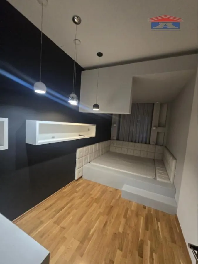 Spavaća soba sa ugrađenim krevetom na uzdignutoj platformi i modernim osvetljenjem.