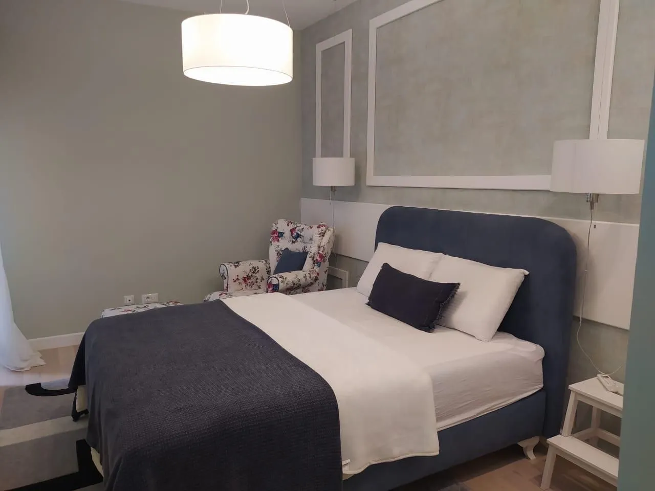 Furnished bedroom with a double bed and an armchair.