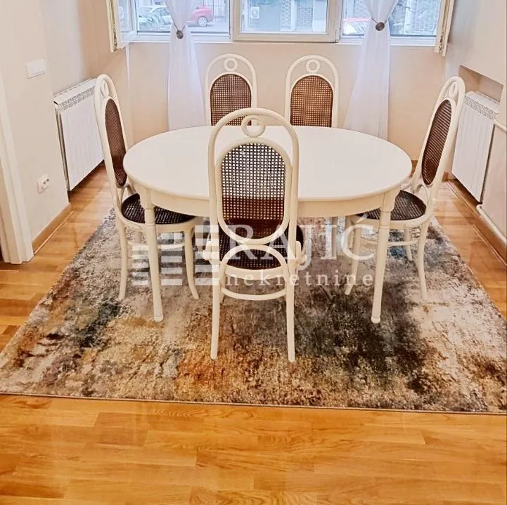Dining area with a white table and chairs on a rug.