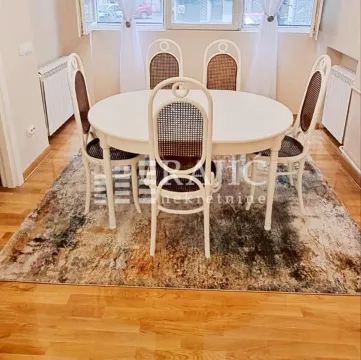 Dining area with a white table and chairs on a rug. - image 7